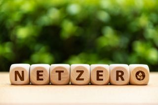 Wooden Blocks Spelling "Net Zero" Against Blurred Green Background